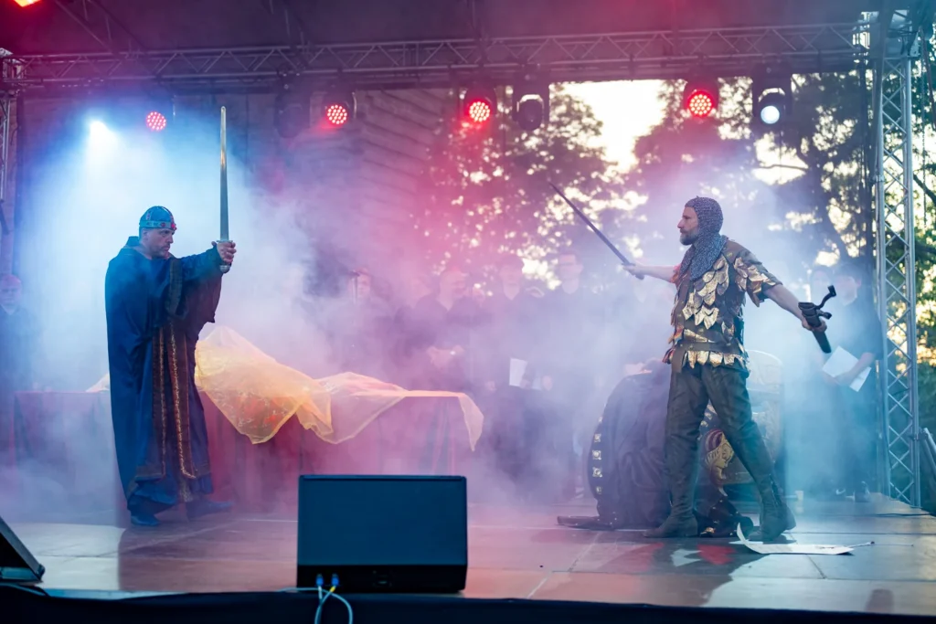 Aktorzy, światło i dym podczas plenerowego widowiska historycznego